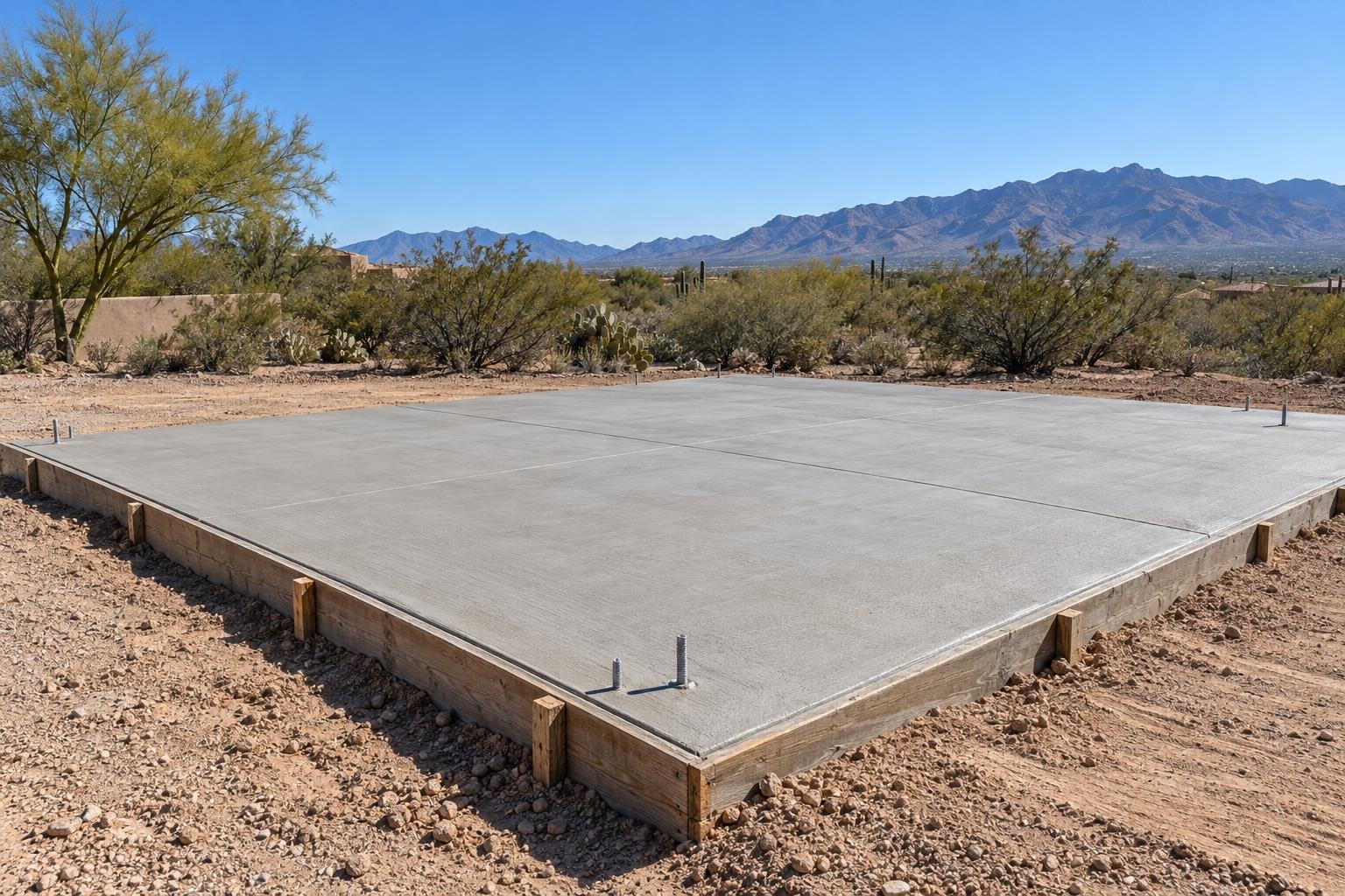 New concrete building pad on open desert ground with mountains behind