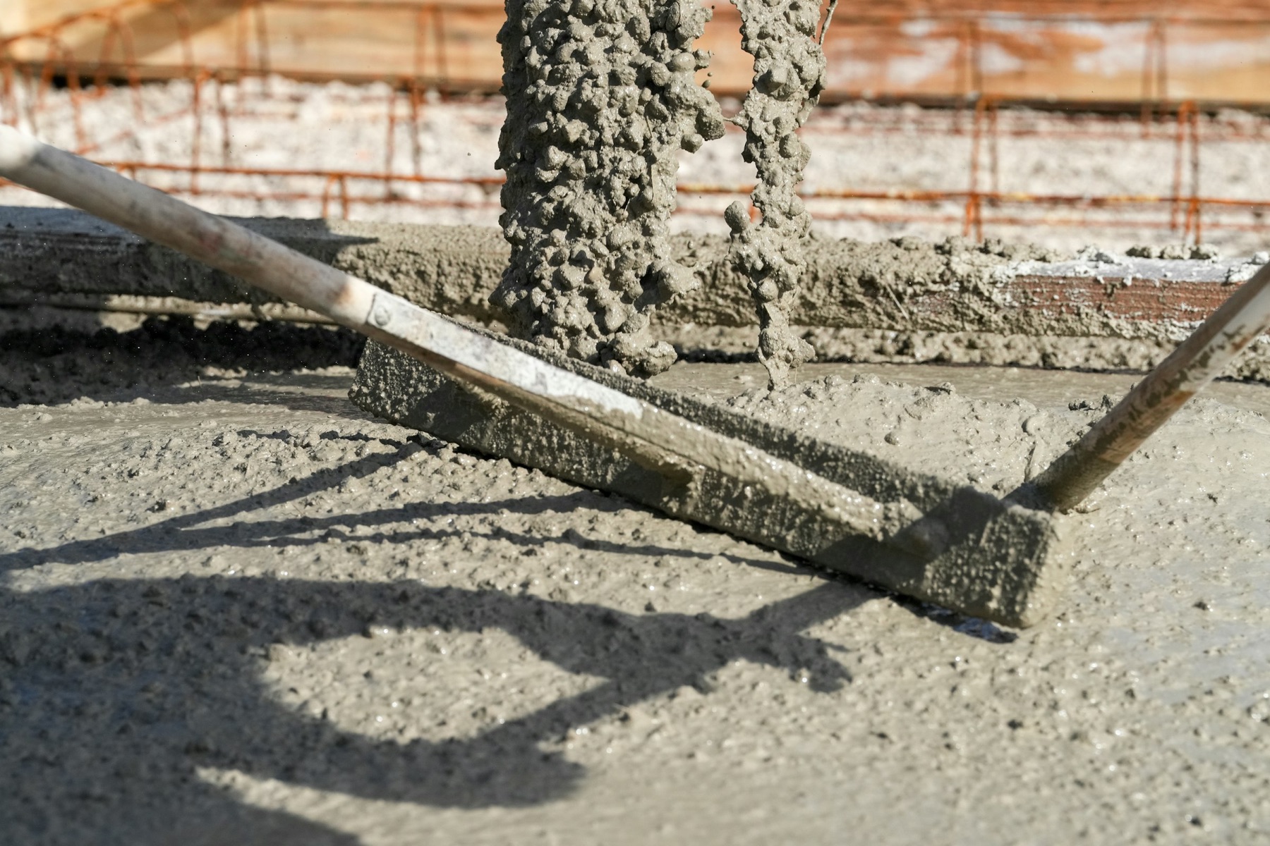Fresh concrete being struck off level with a screed