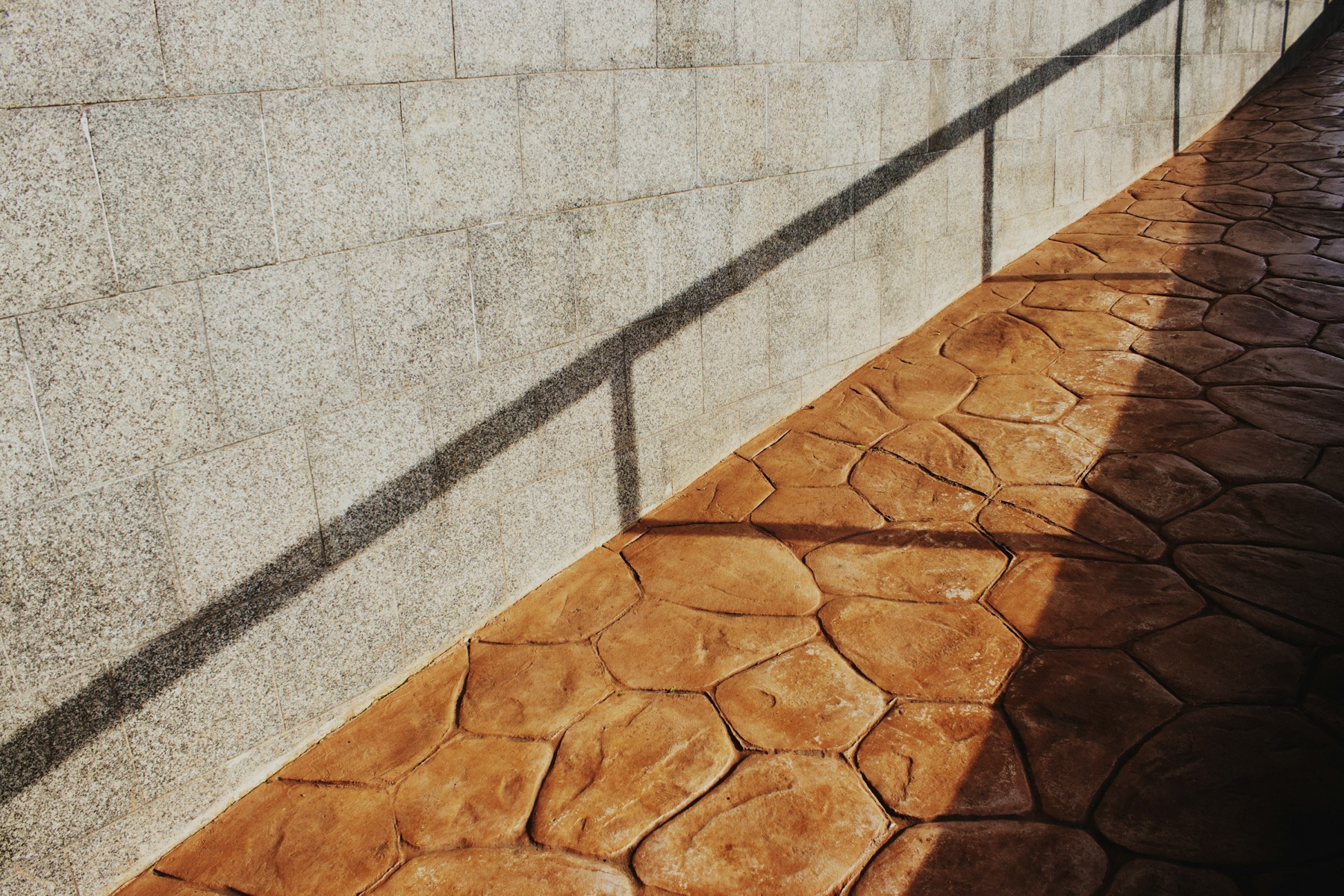 Stamped and colored concrete walkway along a block wall